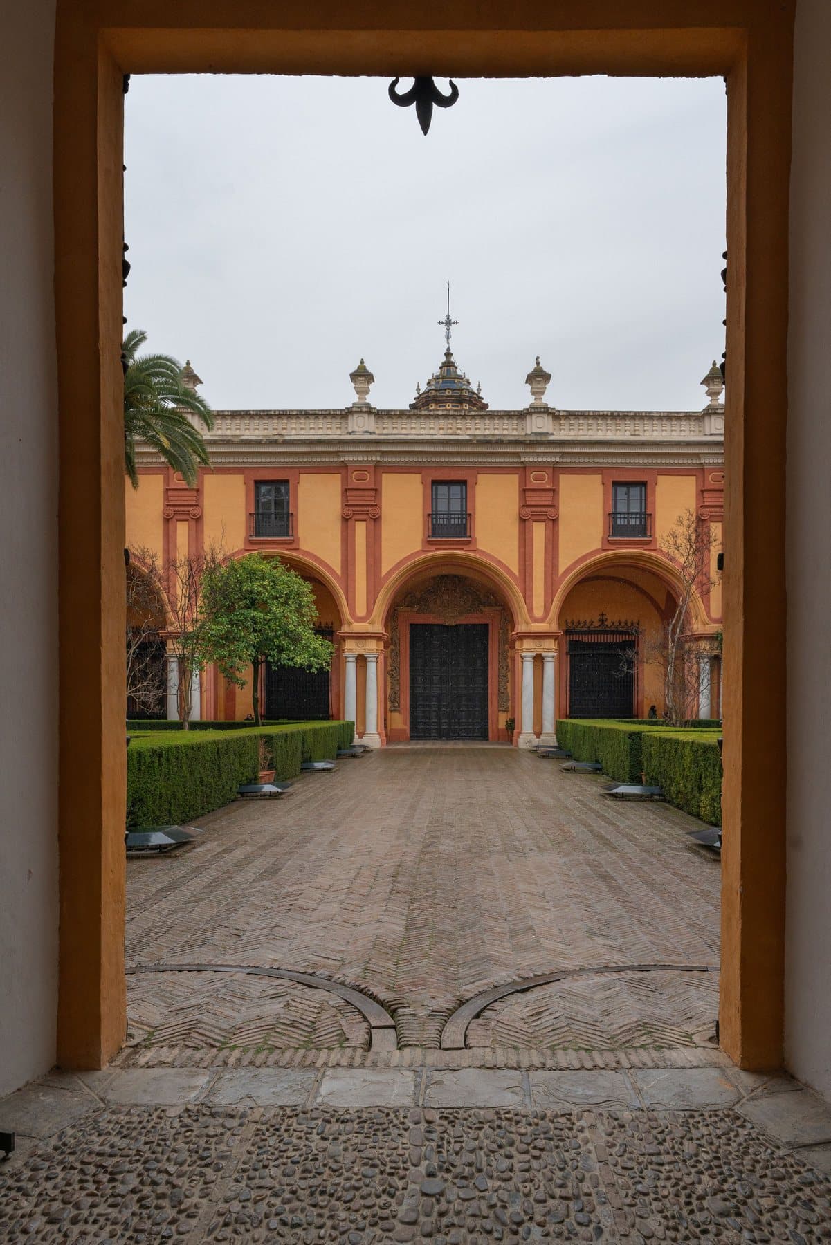 Ein ockerfarbener Innenhof in Sevilla, durch eine Tür gesehen