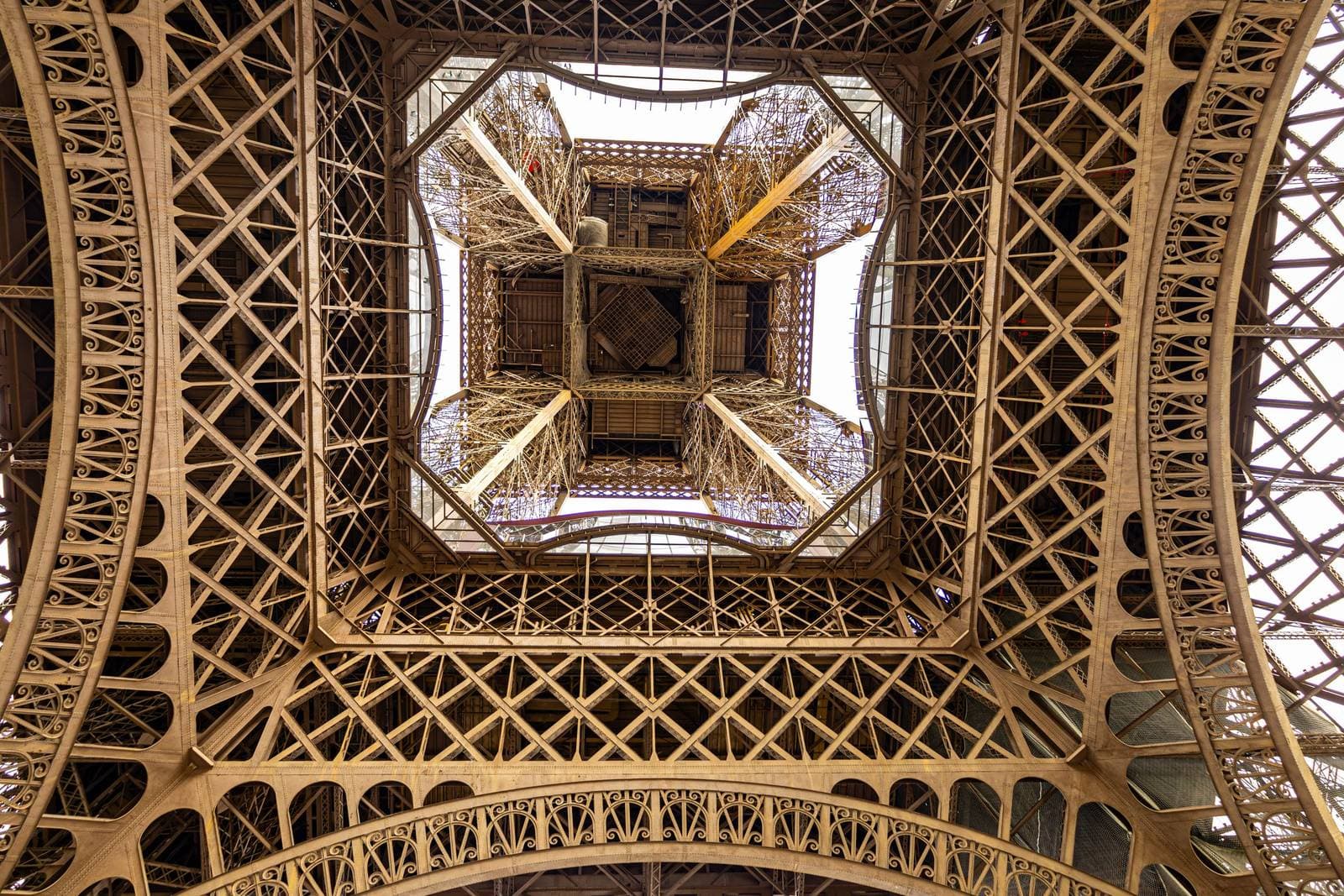 Vista hacia arriba a través del entramado de hierro de la Torre Eiffel