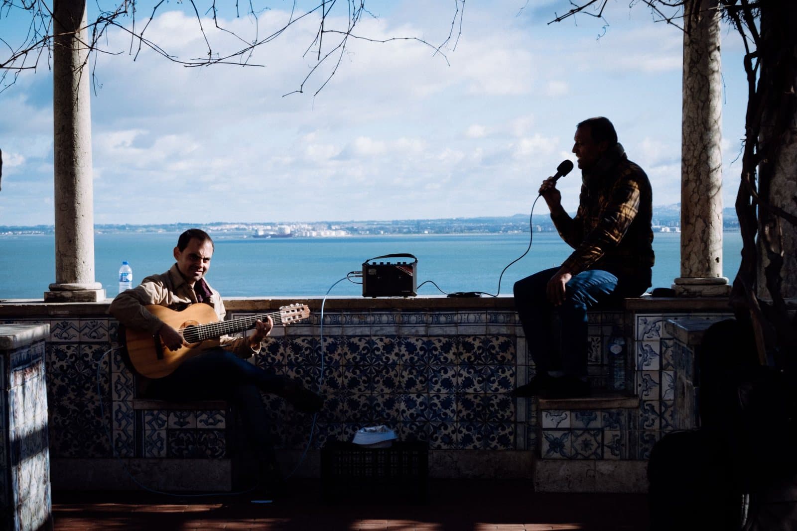 A guitarist and a singer performing at a tiled viewpoint over the Tagus