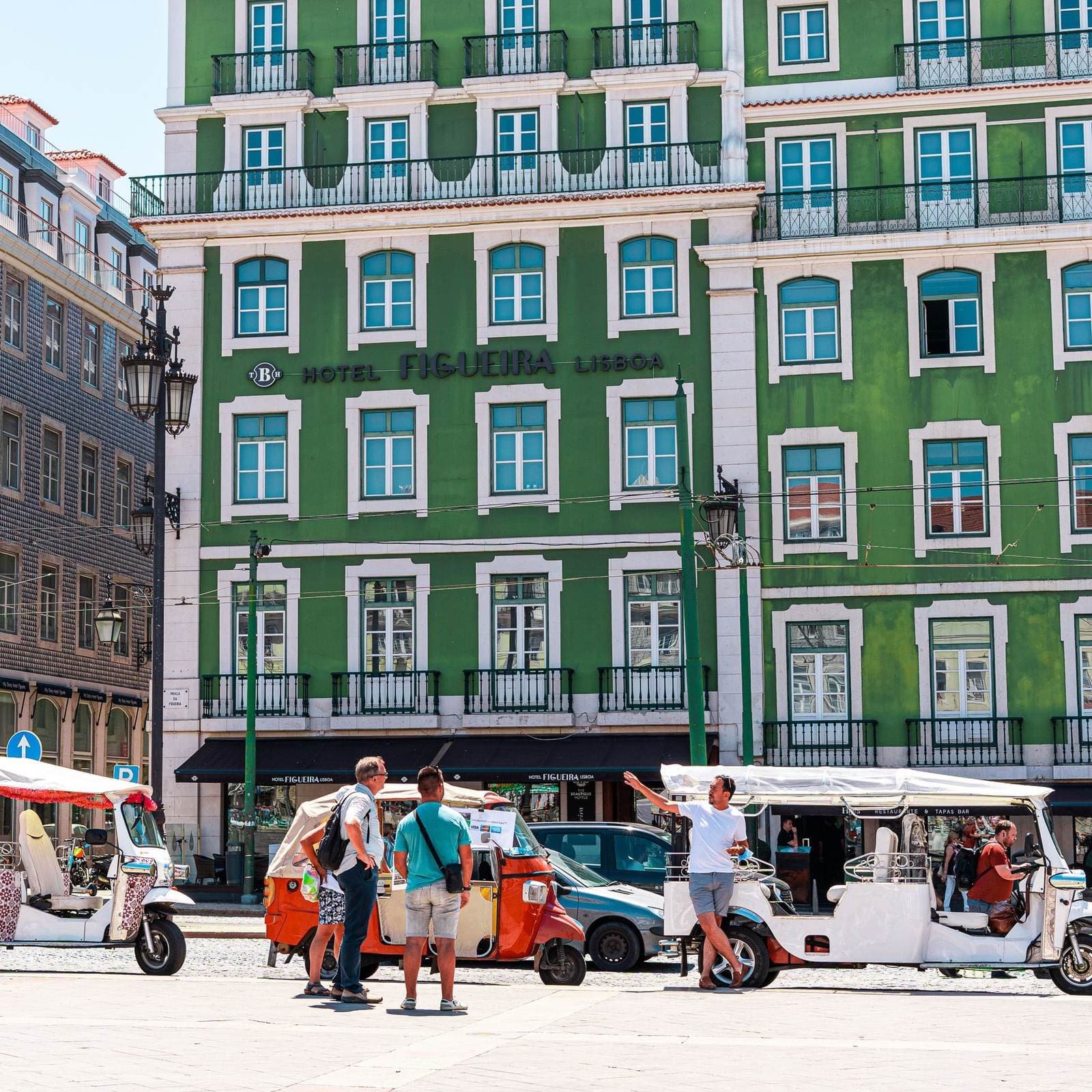Tuk-tuks outside a tiled building in Lisbon