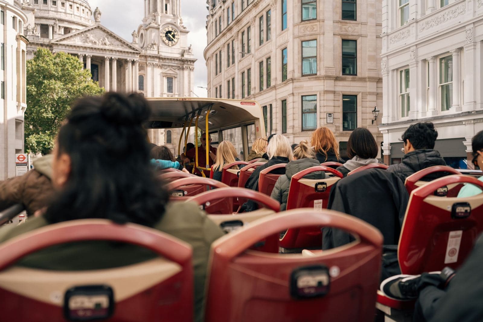 Reisende auf dem offenen Oberdeck eines Londoner Sightseeing-Busses, von hinten gesehen
