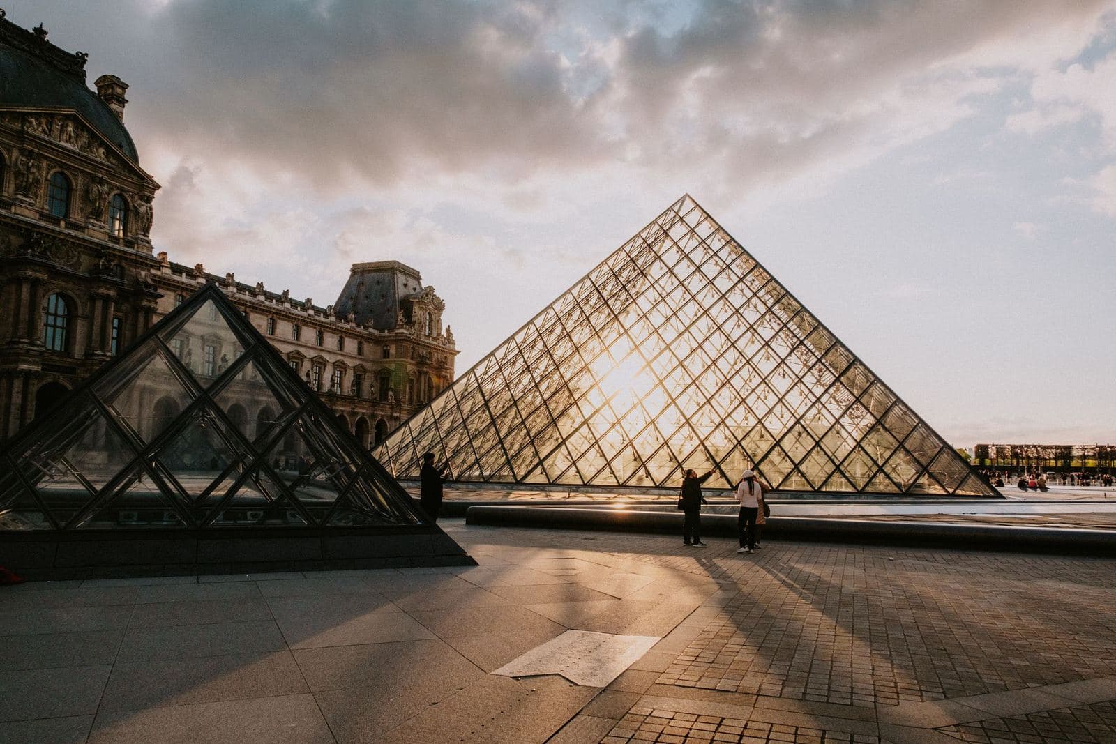Louvre pyramid against the low sun, with the palace behind