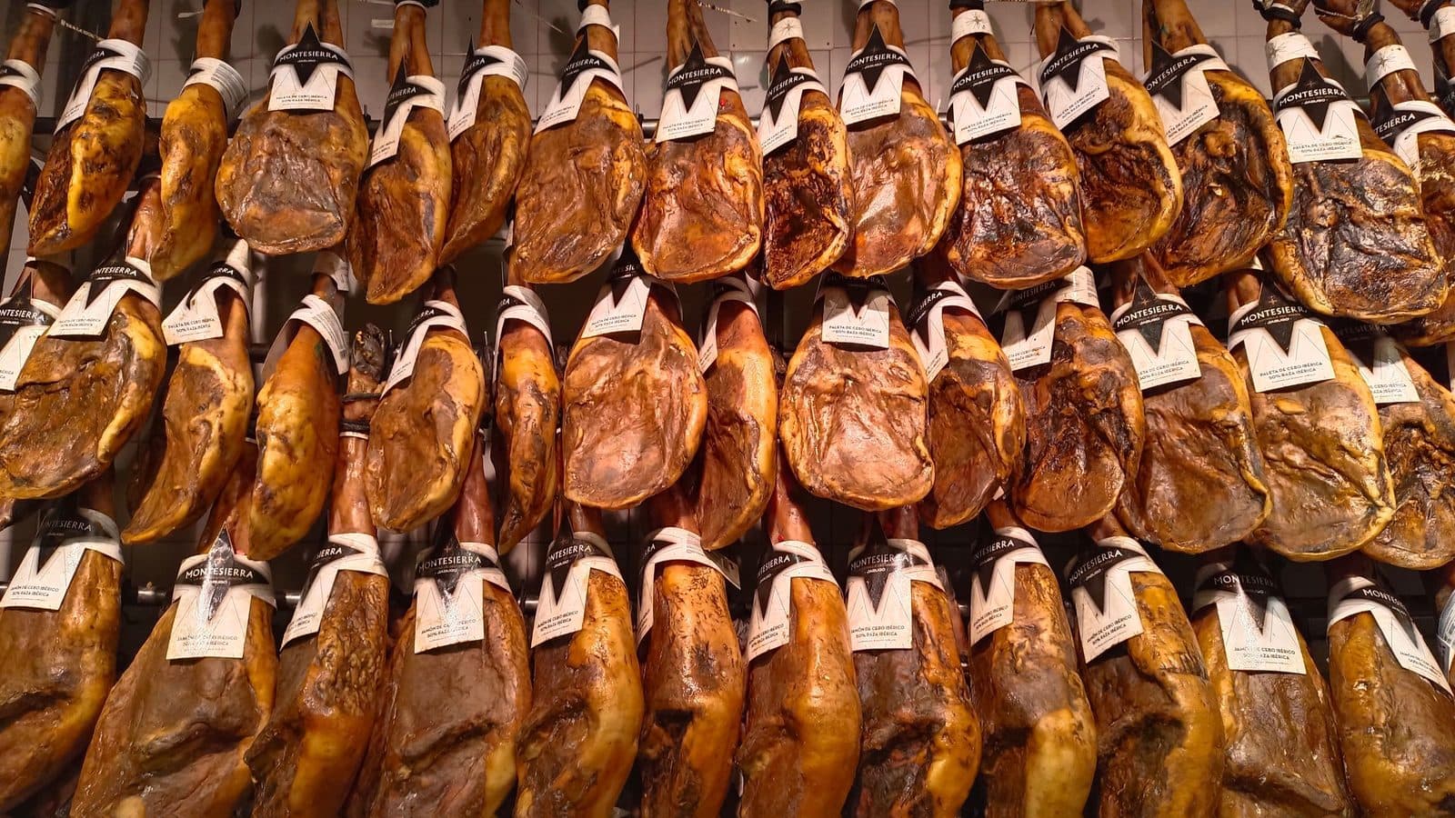 Rows of jamón ibérico hanging in a Madrid market