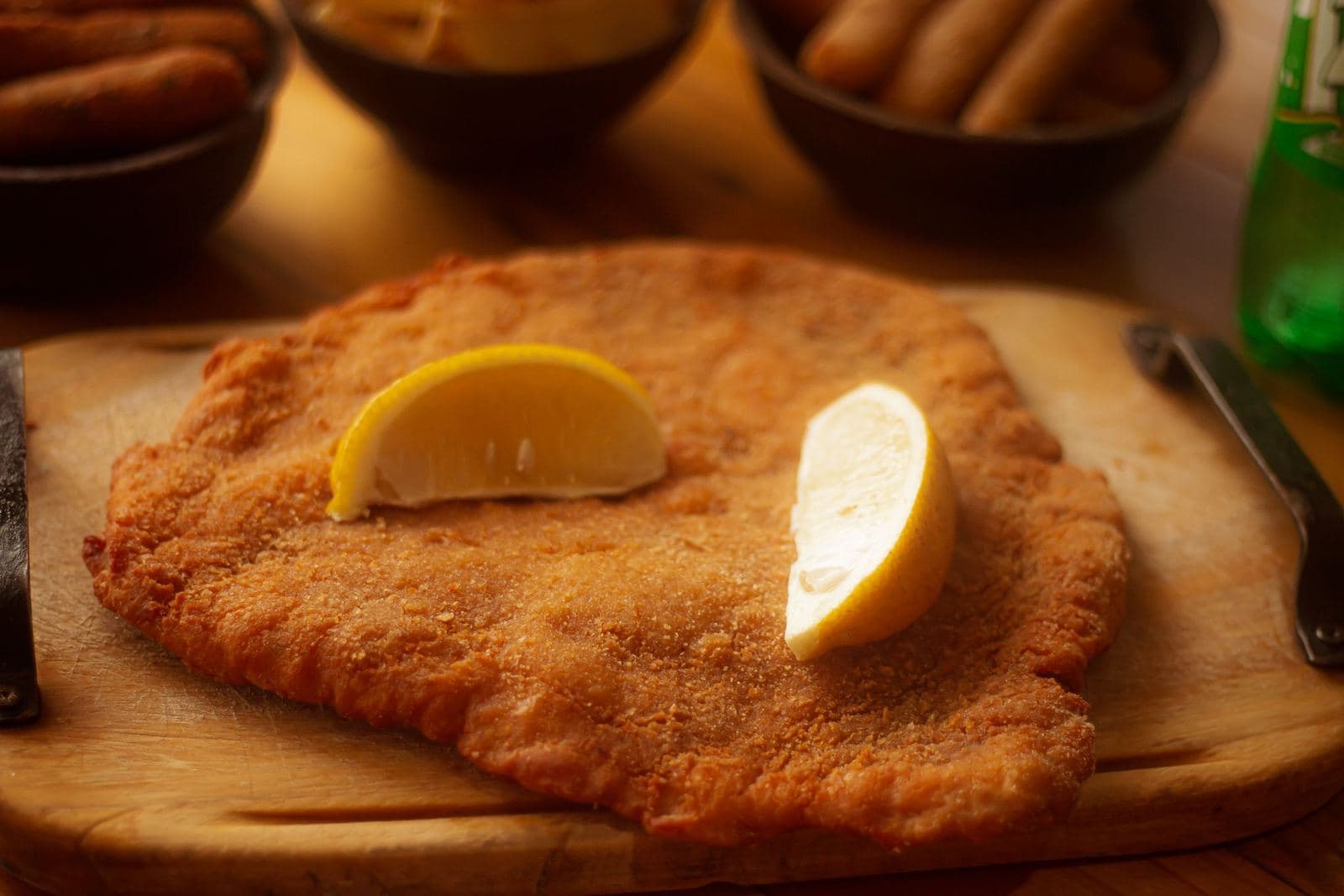 Breaded cutlet with lemon wedges, in the style of a cotoletta