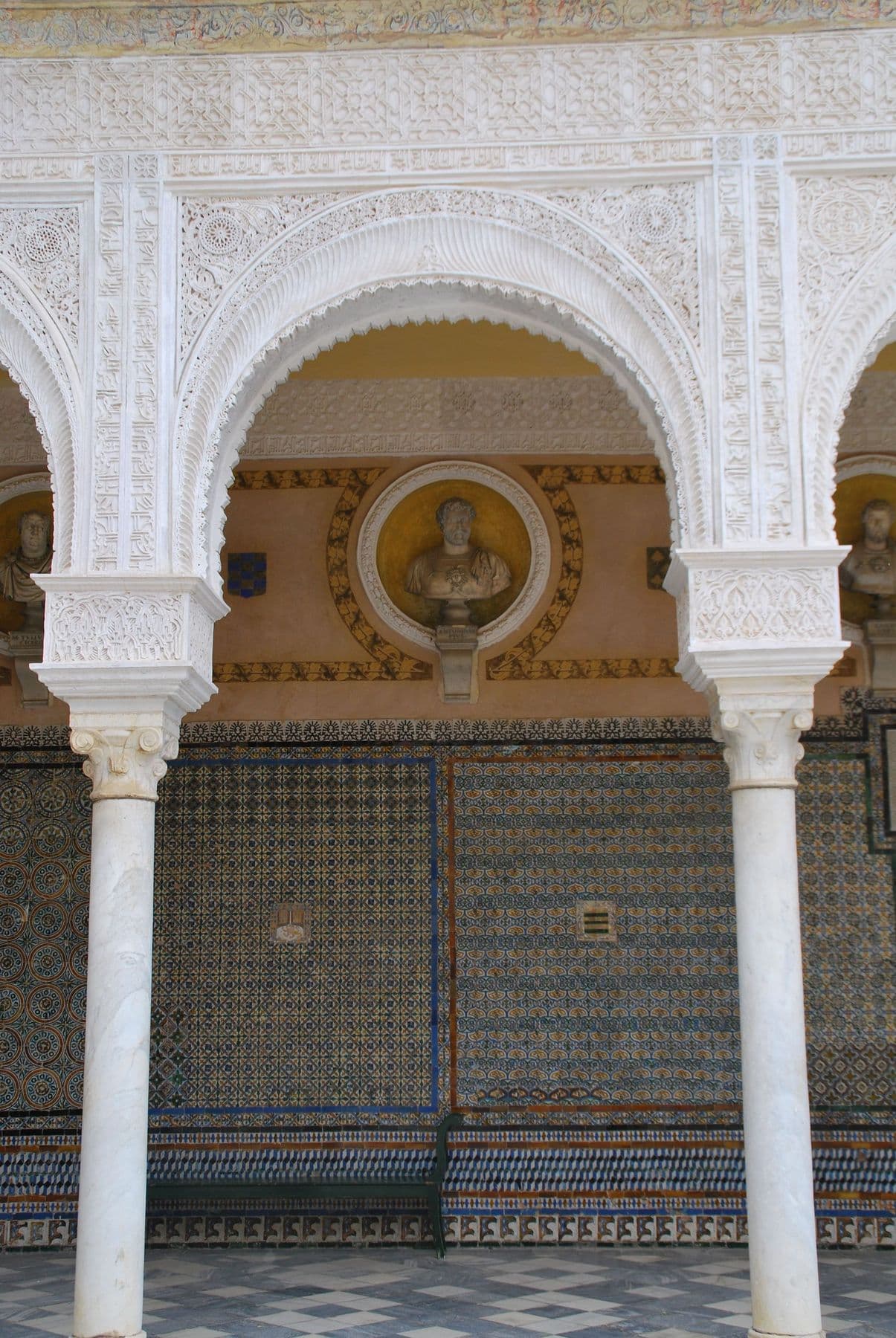 Marble arches, a medallion bust and tiled walls in the courtyard of the Casa de Pilatos