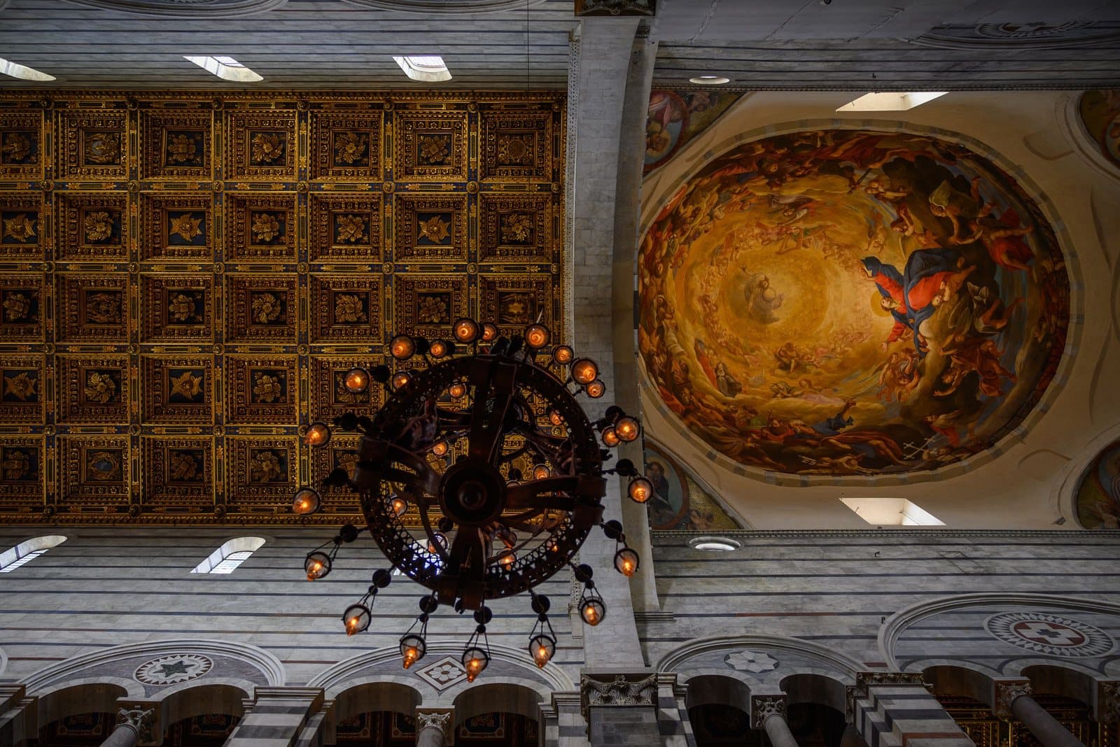 Die vergoldete Decke, eine Bronzelampe und das Kuppelfresko im Dom von Pisa