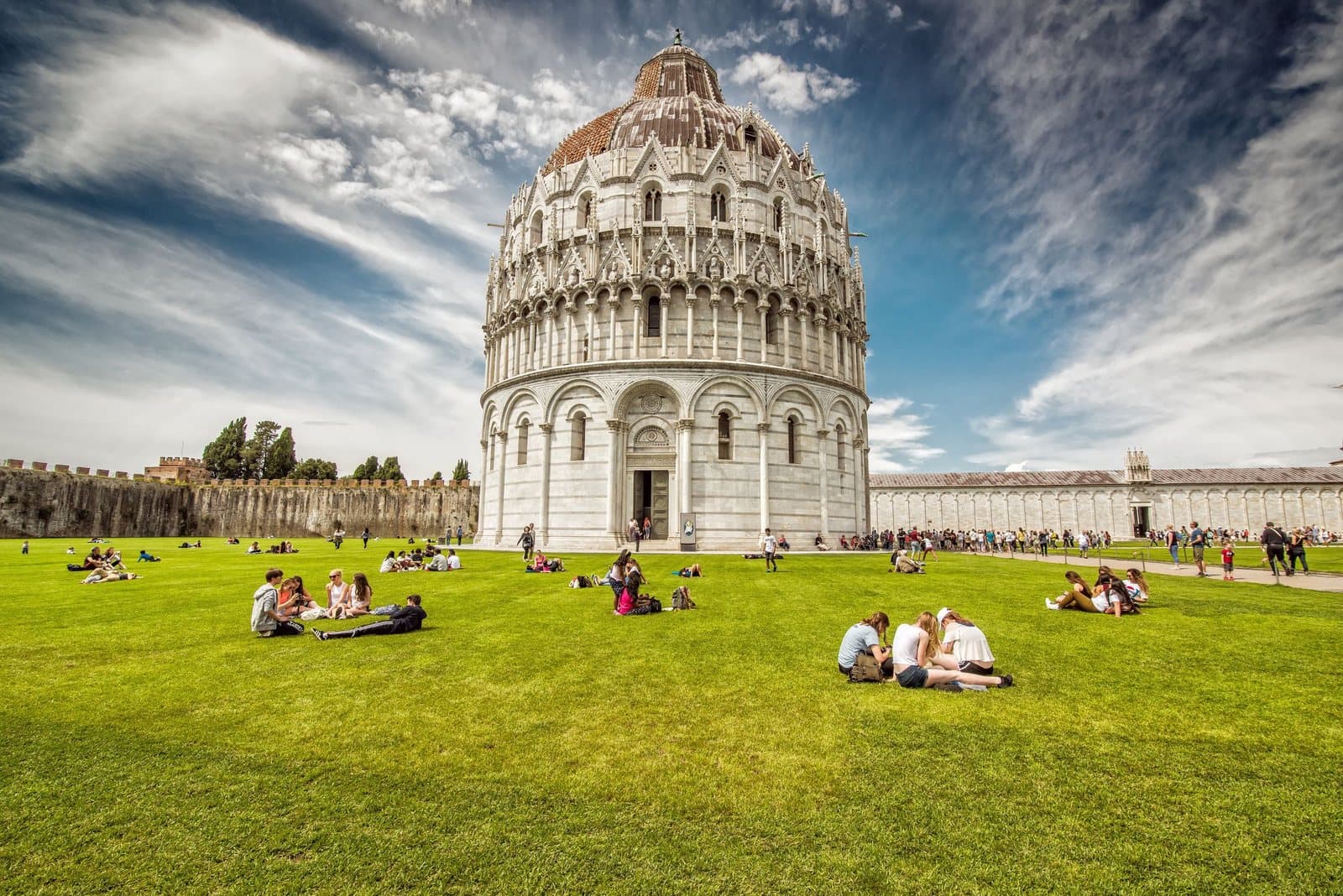 Besucher auf dem Rasen der Piazza dei Miracoli vor dem Baptisterium