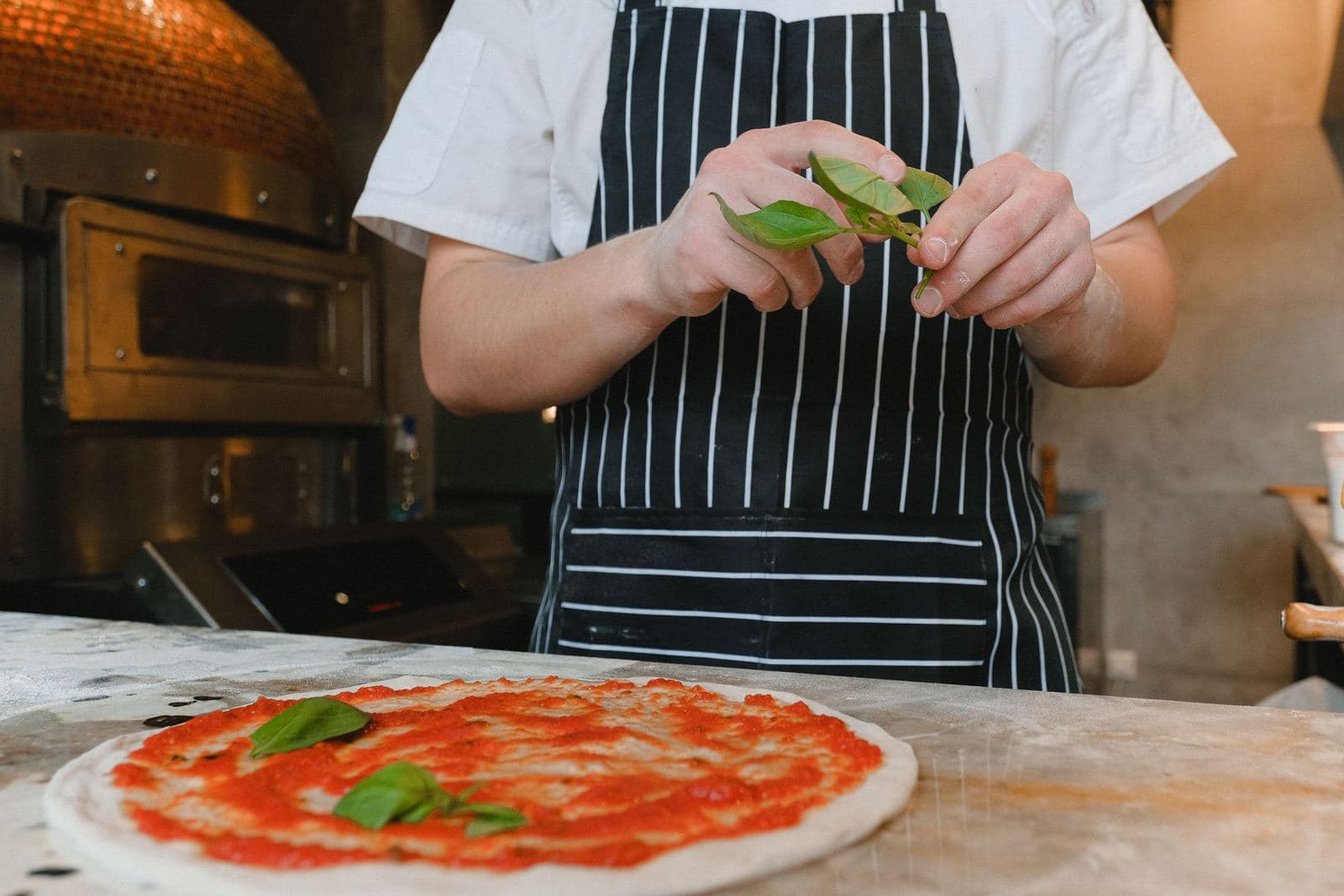 Adding fresh basil to a pizza in a kitchen