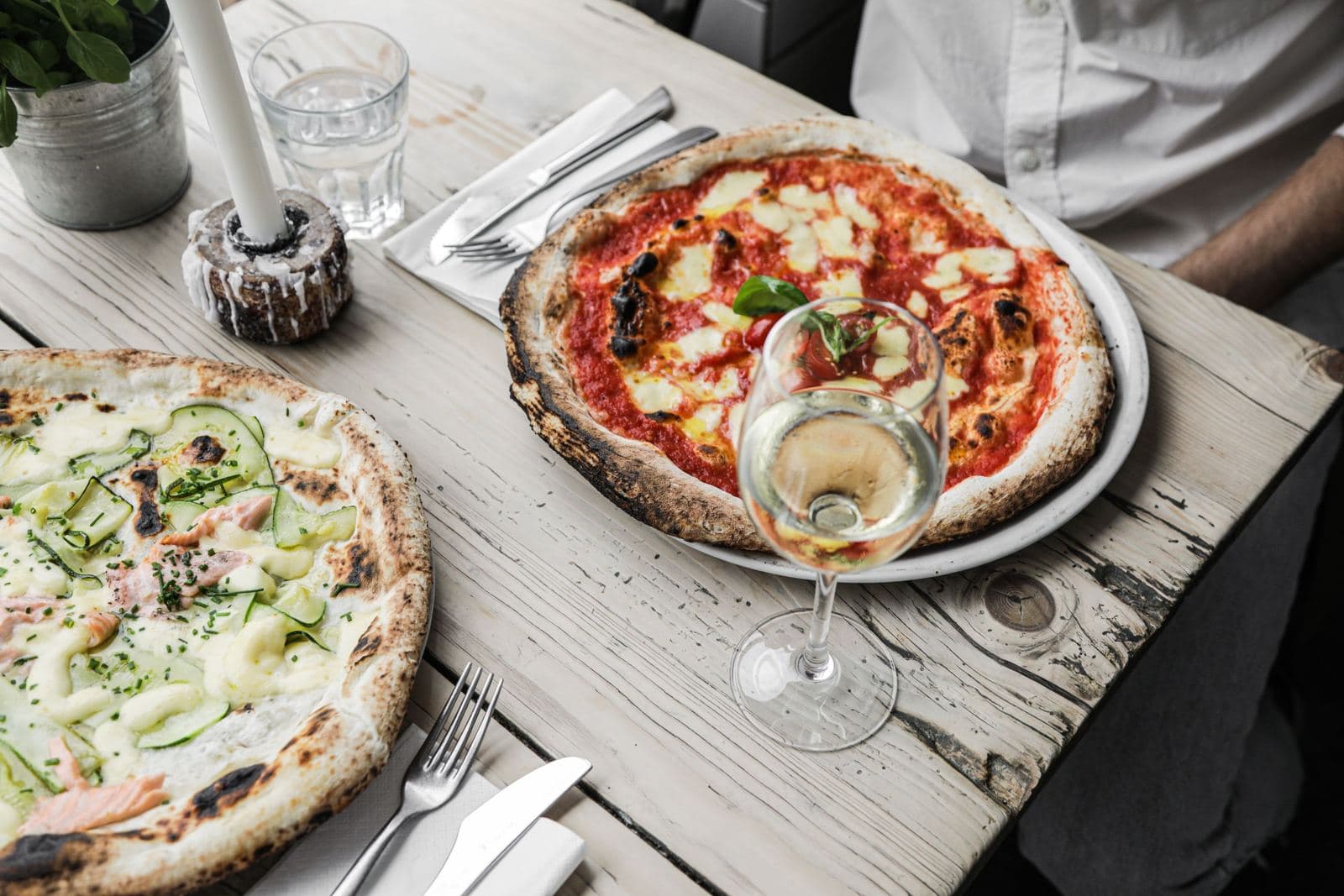 Pizzas and white wine on a wooden table