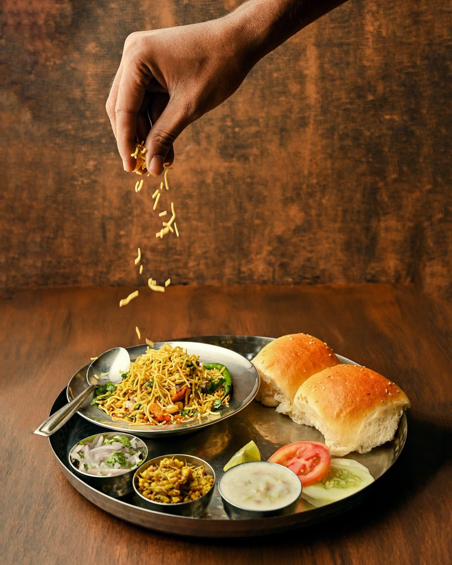 Farsan sprinkled over a plate of misal, served with pav