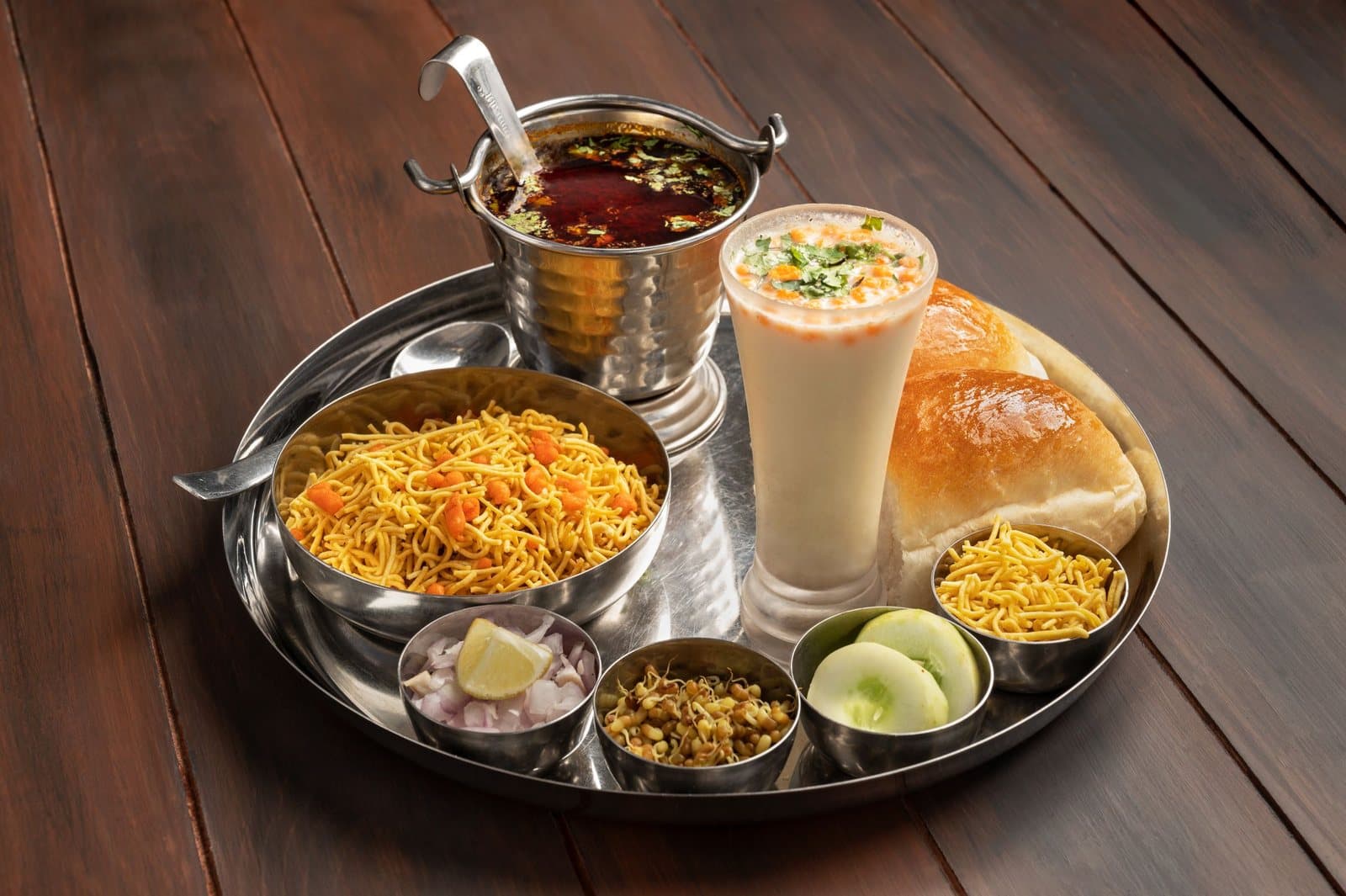 A tray of misal pav with farsan and buttermilk