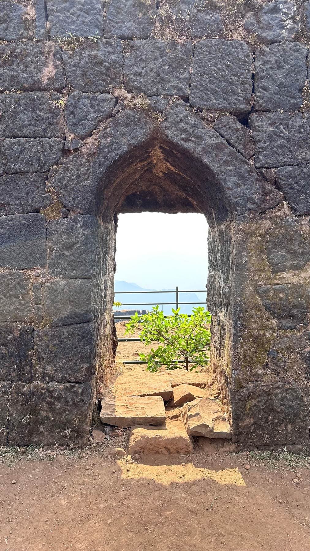 A stone archway on a hill fort near Pune, framing the valley