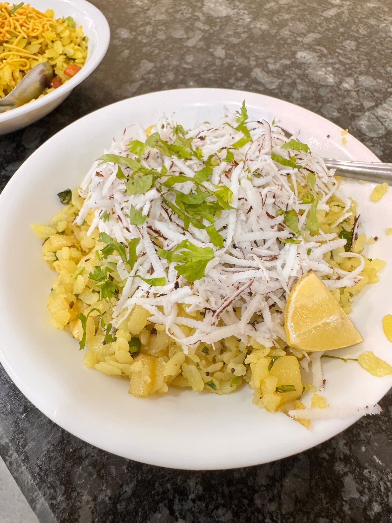 A plate of poha topped with coconut, a Maharashtrian breakfast