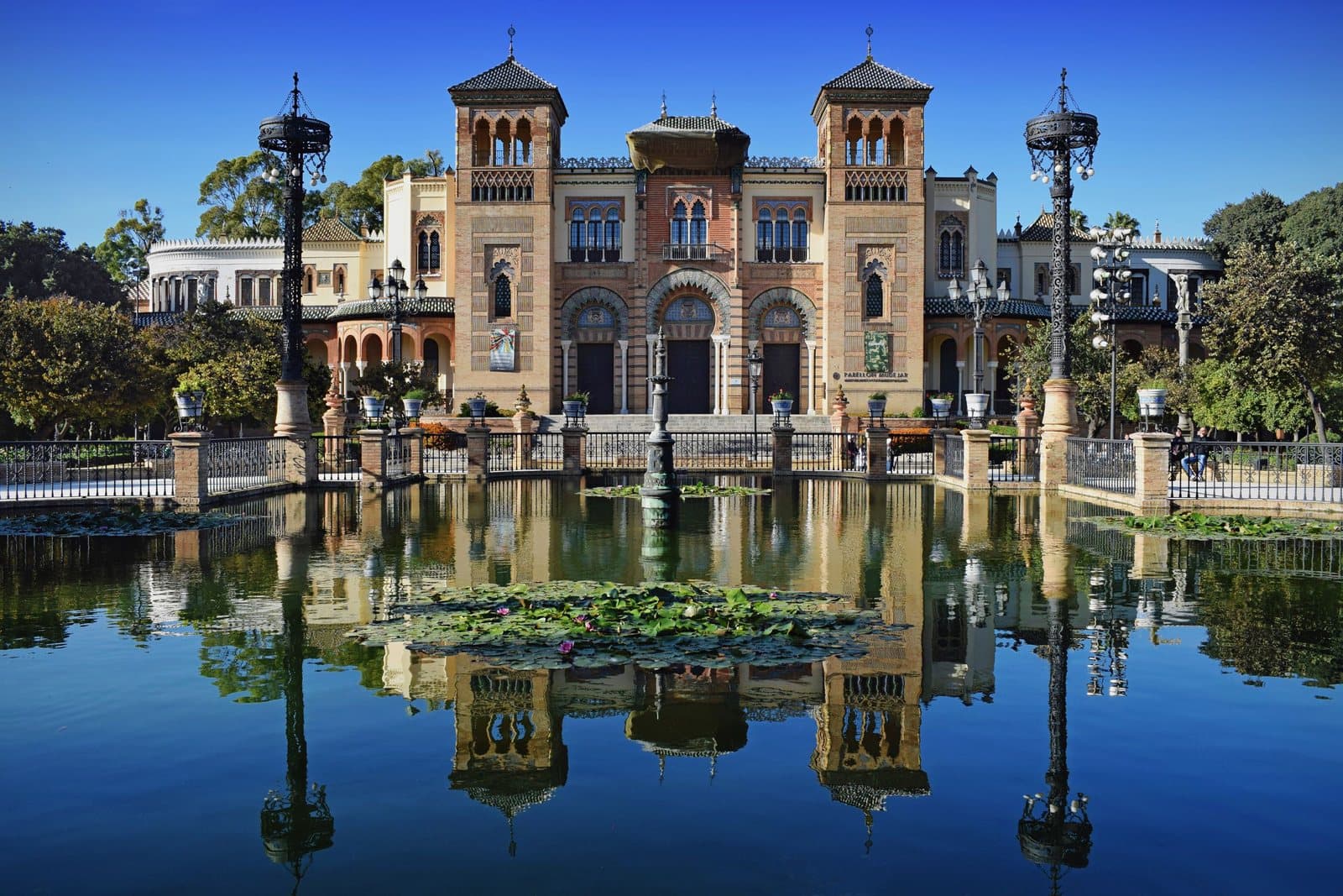 Ein Pavillon spiegelt sich in einem Teich im María-Luisa-Park