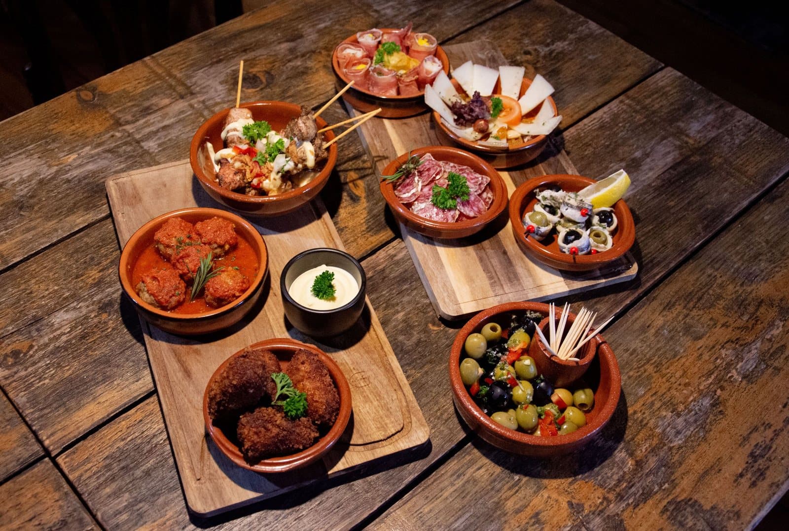 Tapas in clay dishes on wooden boards