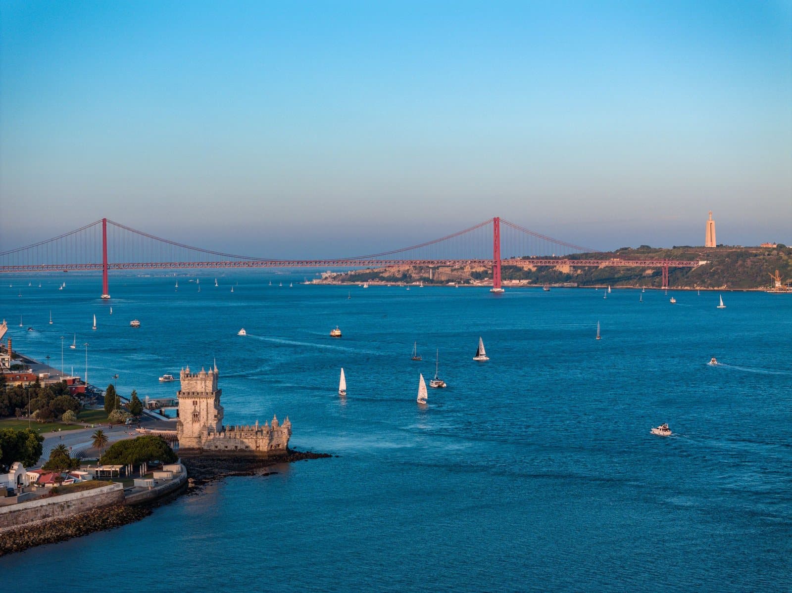 Sailboats on the Tagus near Belém Tower, with the 25 de Abril Bridge in the distance