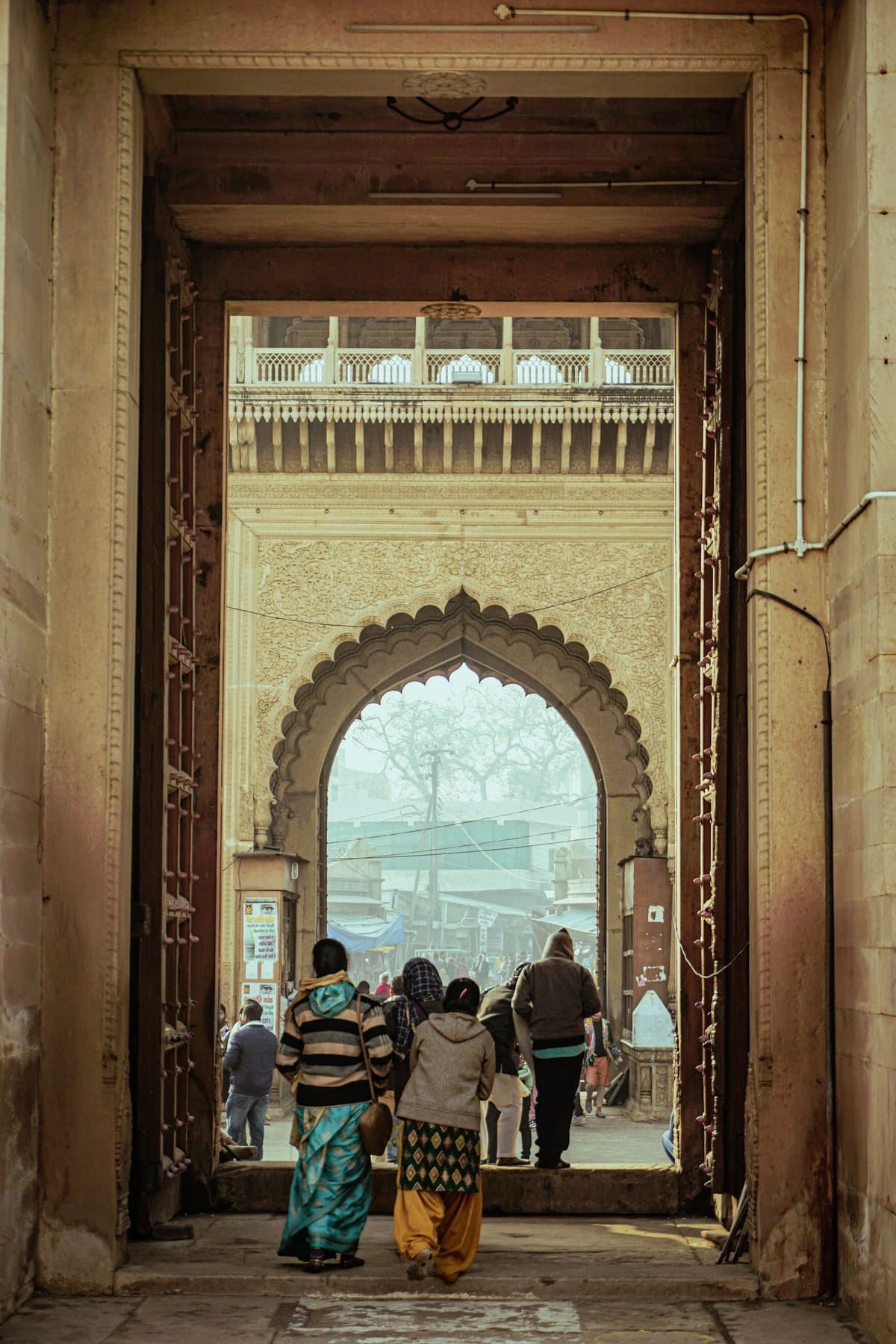 People walking through a carved archway in Vrindavan's old town