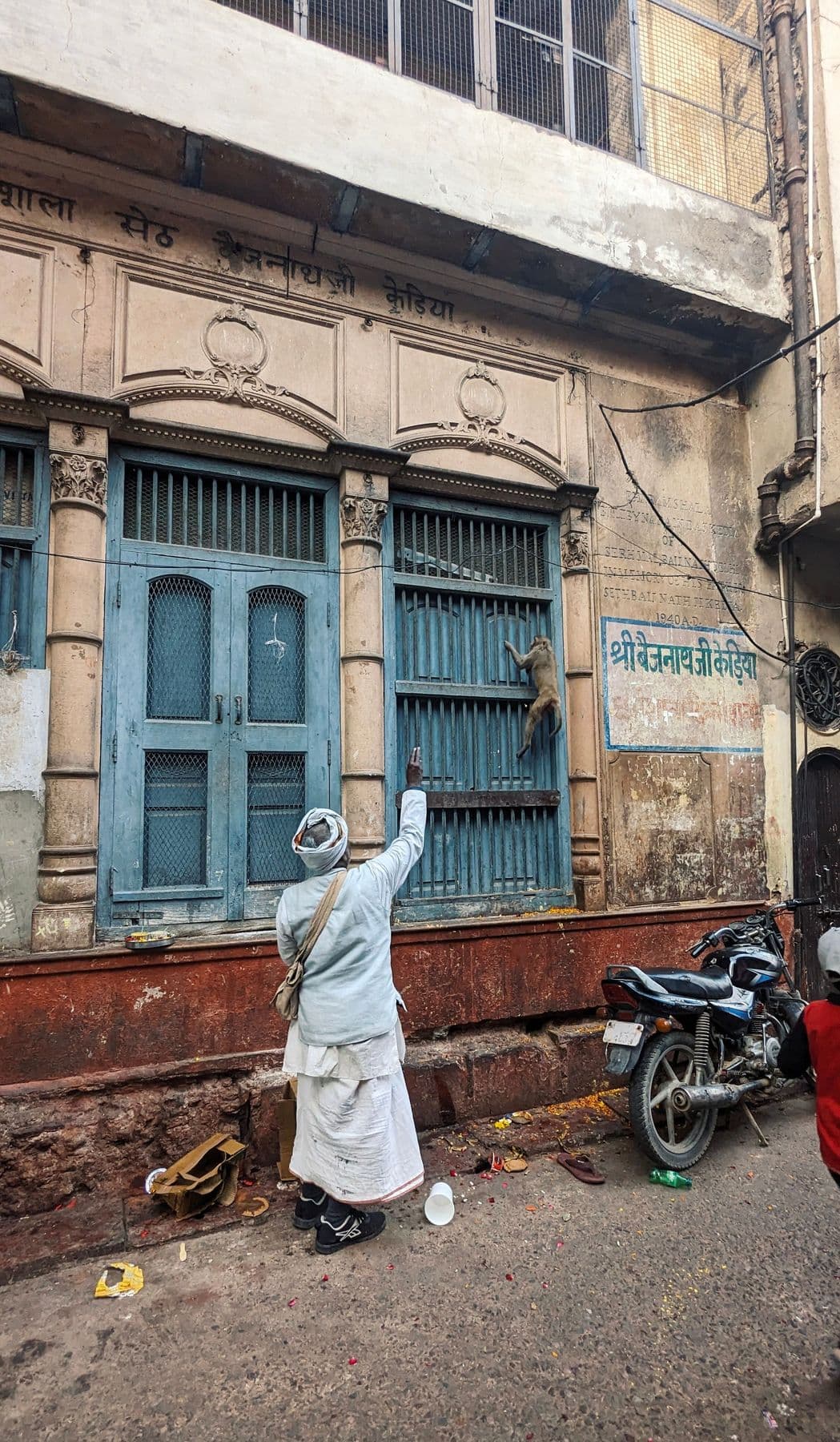 A man feeding a monkey on a wall in a Vrindavan lane