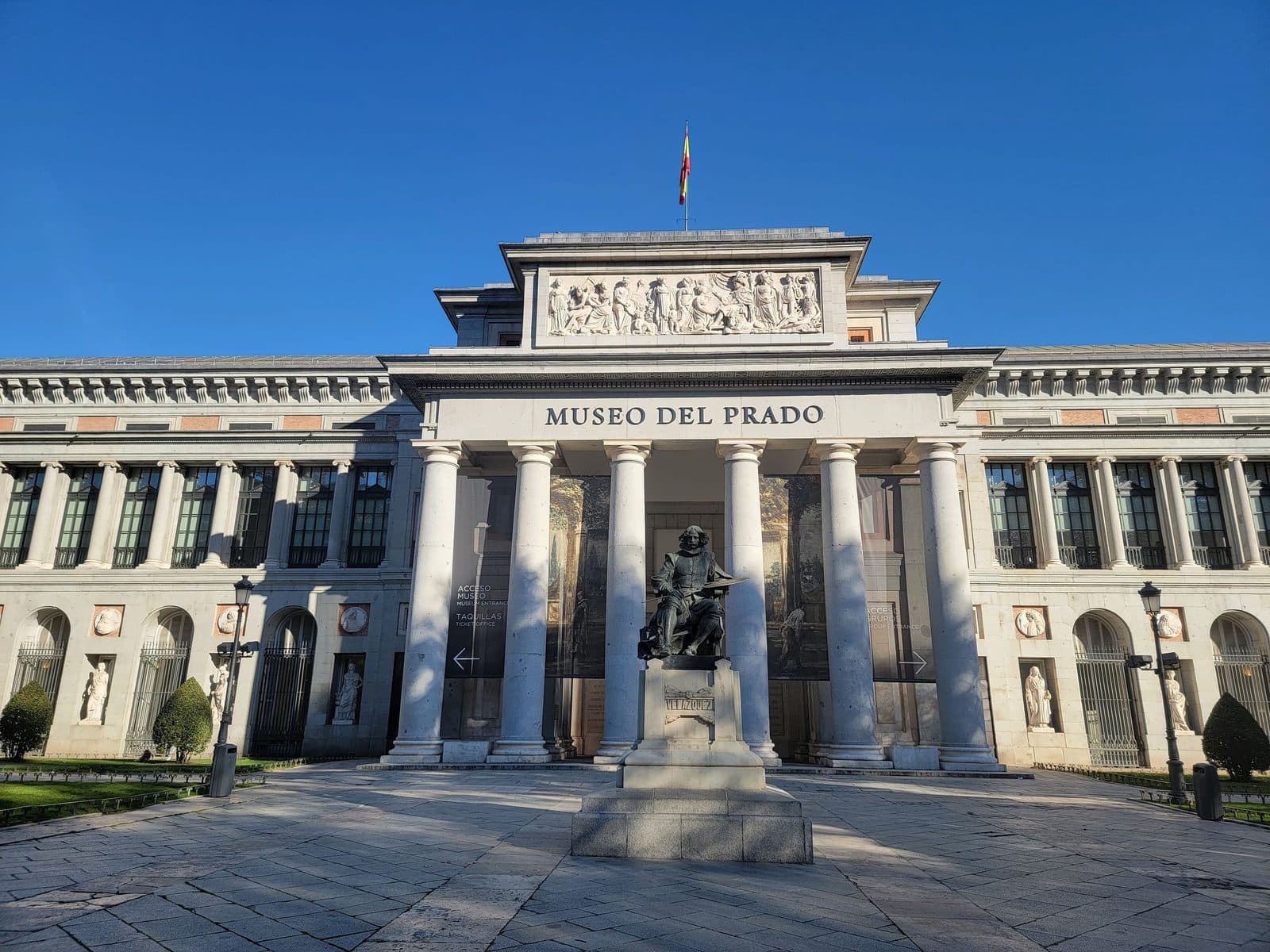 Main façade of the Prado Museum under a clear blue sky