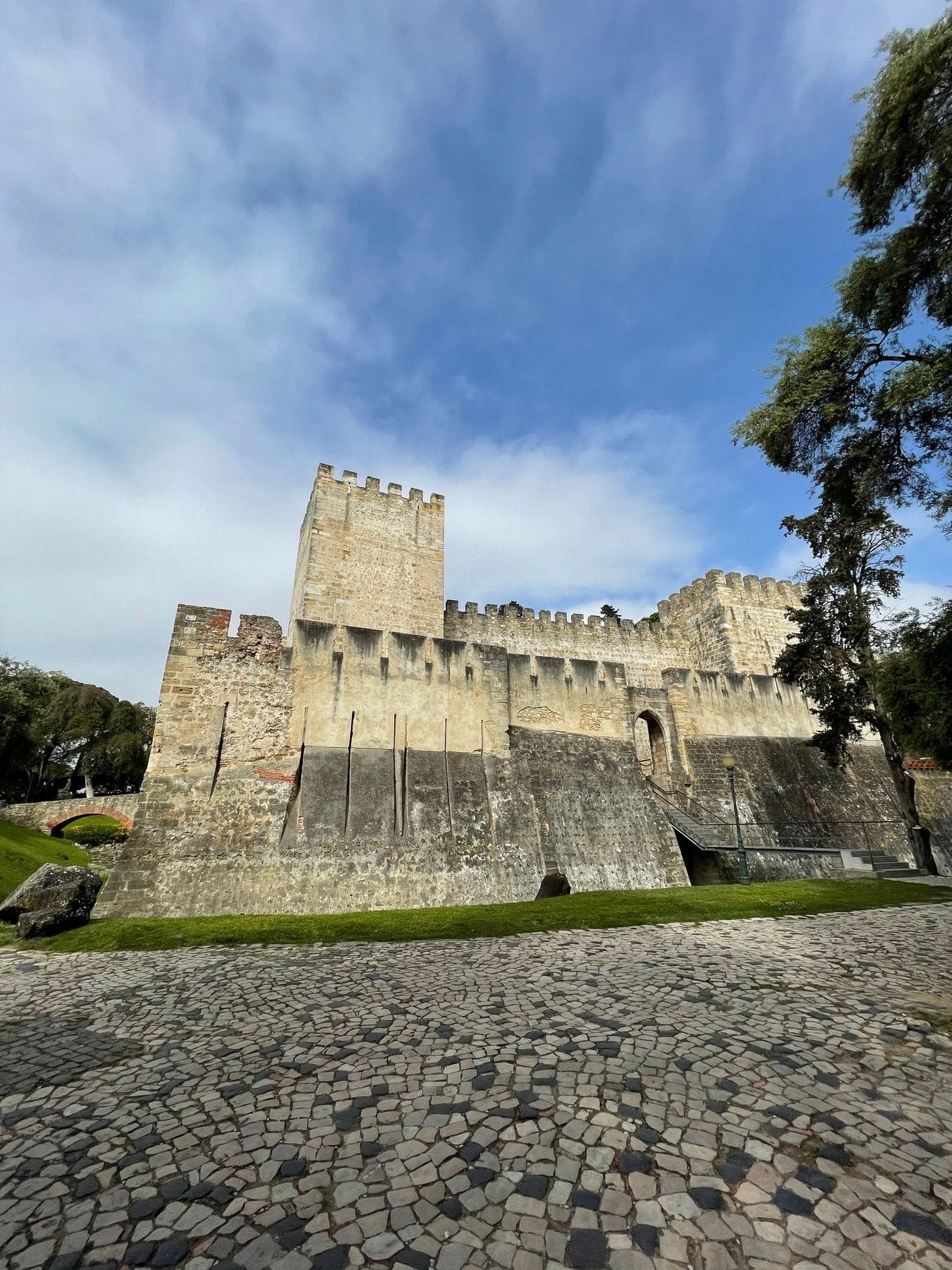 The stone walls and towers of São Jorge Castle under a blue sky